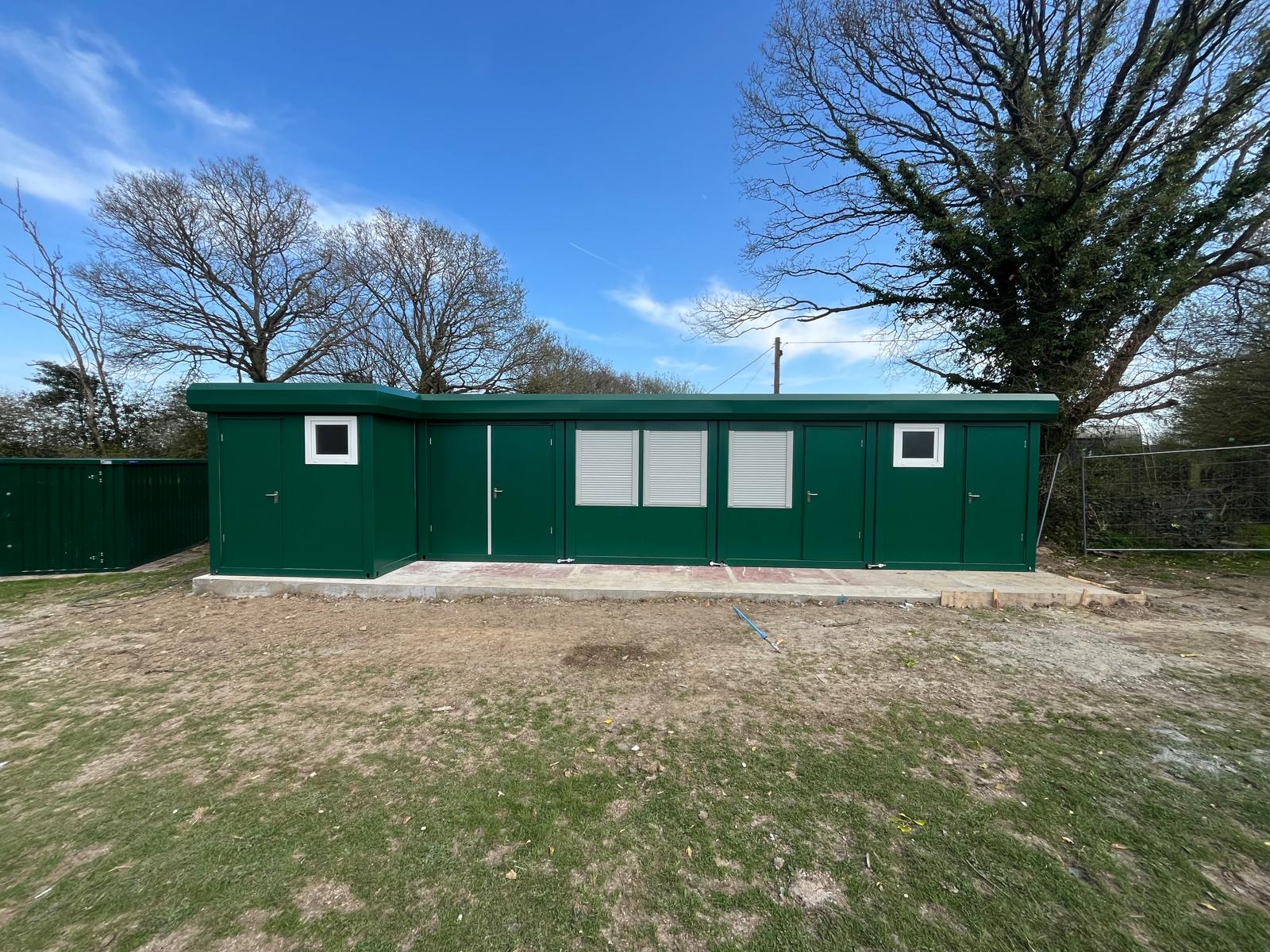 A completed green Containex modular building installed on a concrete base on a site in Sussex